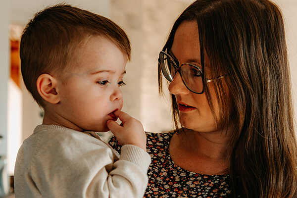 Theo mit seiner Mutter Eine Frau mit langen dunklen Haaren hält einen kleinen Jungen (etwa zwei Jahre alt) auf dem Arm.